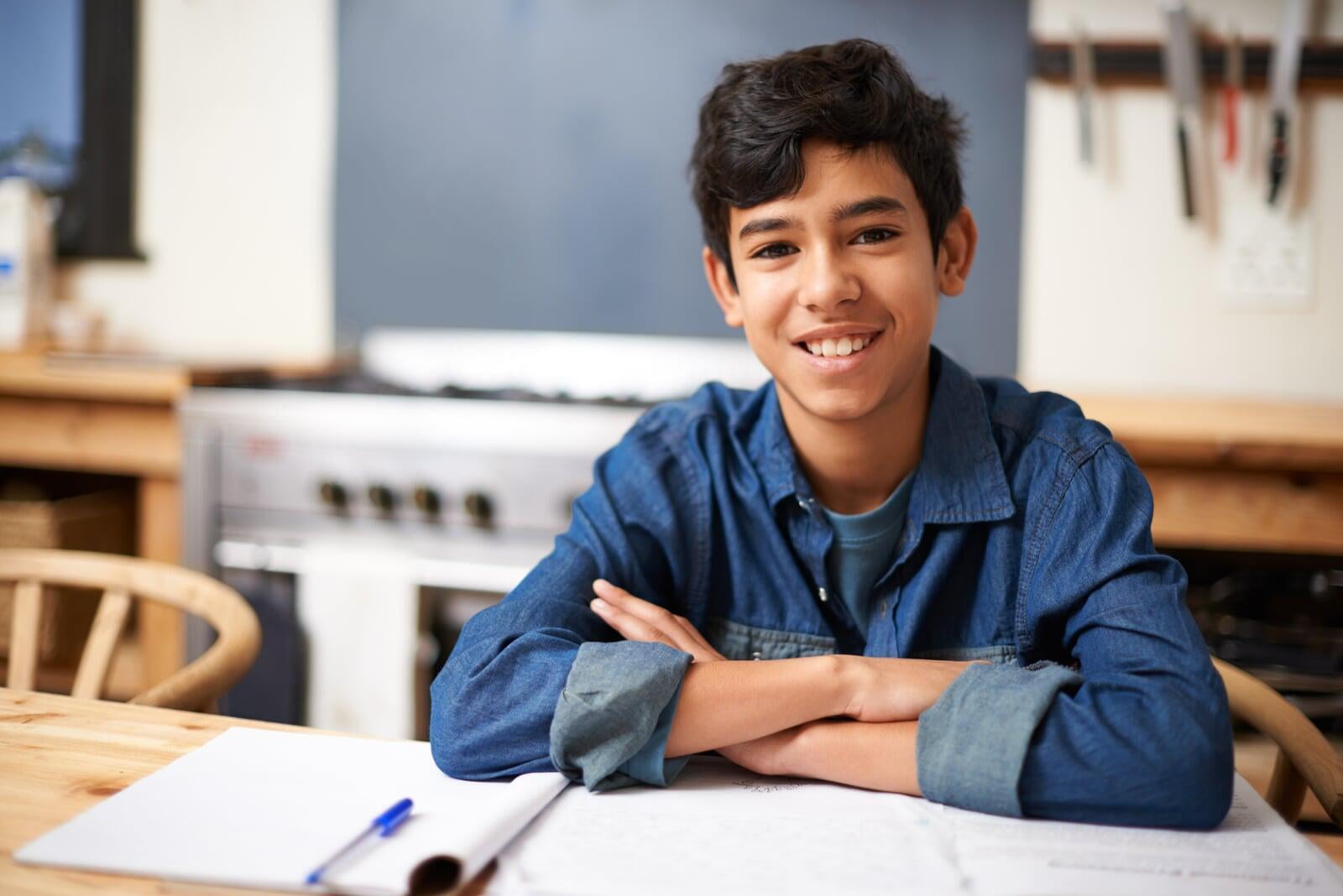 Middle school aged student at desk with arms crossed. 